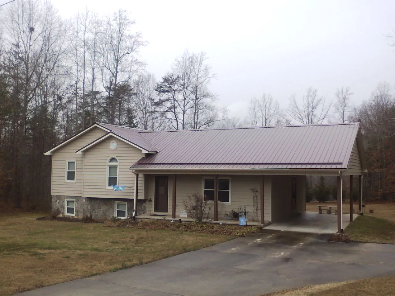 Burgundy metal roof on a tan split level home with an attached carport in Nelson