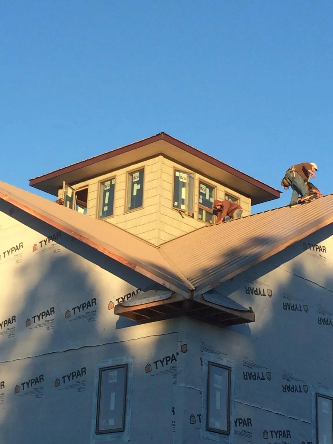Roofers working around a rooftop cupola on a new metal roof at sunset — Roof Waterproofing in Nelson by Roofing Brothers